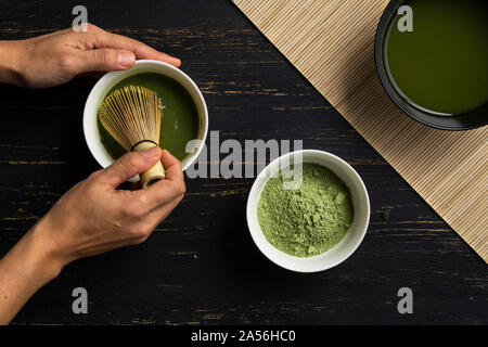 Die Frau Hände mischen Matcha Grüntee Pulver in eine Schüssel, Ansicht von oben Stockfoto