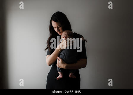 Junge Frau mit Baby Sohn in die Arme, Low Key Stockfoto