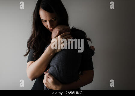 Junge Frau mit Baby Sohn in die Arme, Low Key Stockfoto
