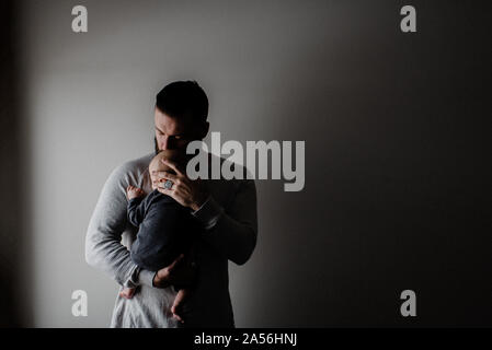 Junger Mann, der Sohn in den Armen, Low Key Stockfoto