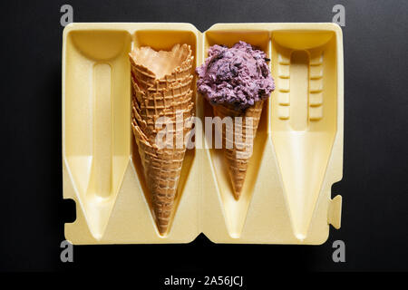 Eis Kegel und Stapel von Waffeln in der Verpackung auf schwarzem Hintergrund, Ansicht von oben Stockfoto