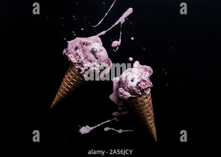 Zwei Chocolate Chip himbeere Eistüten mit geschmolzenem Splash auf schwarzem Hintergrund, Ansicht von oben Stockfoto
