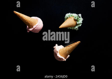 Drei Eistüten, Minze, Chocolate Chip und Erdbeere auf schwarzem Hintergrund, Ansicht von oben Stockfoto