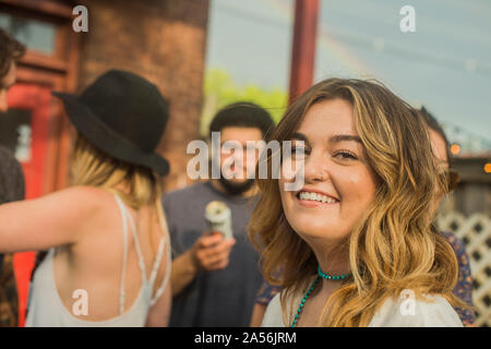 Junge Frau mit männlichen und weiblichen Freunde auf der Gartenparty, Kopf und Schulter portrait Stockfoto