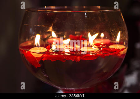 Rote Kerze leuchtet in einem großen glassess für Valentinstag. Stockfoto