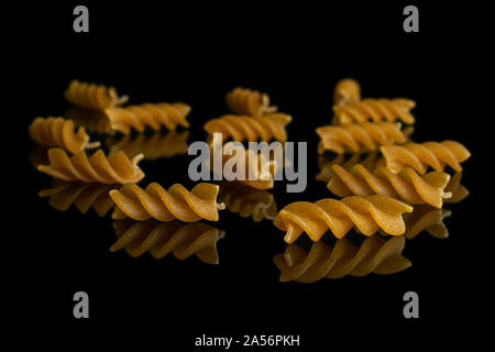 Menge ganz trocken braun Vollkorn fusilli auf schwarzem Glas isoliert Stockfoto