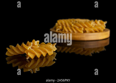 Menge ganz trocken braun Vollkorn fusilli auf Bambus Untersetzer auf schwarzem Glas isoliert Stockfoto