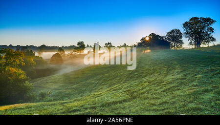 Bauernhof bei Sonnenaufgang mit Nebel. Stockfoto