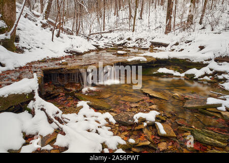 Kleiner Wasserfall in einem Schnee Szene. Stockfoto