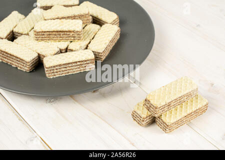 Menge ganze knusprige beige hazelnut Wafers Cookie auf grau Keramikplatte auf weißem Holz Stockfoto