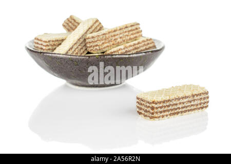 Menge ganze knusprige beige hazelnut Wafers Cookie in dunkle Keramik Schüssel auf weißem Hintergrund Stockfoto