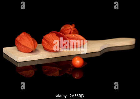 Gruppe von fünf ganze Frische orange Physalis auf Holz Schneidebrett auf schwarzem Glas isoliert Stockfoto