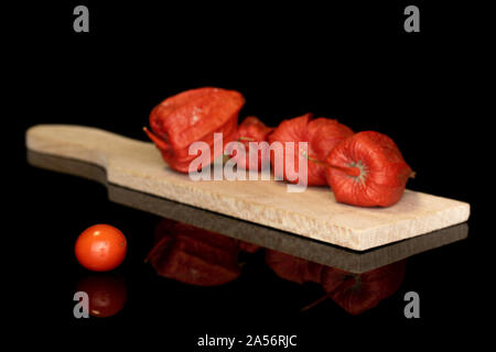 Gruppe von fünf ganze Frische orange Physalis auf Holz Schneidebrett auf schwarzem Glas isoliert Stockfoto