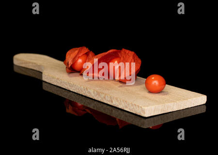 Gruppe von drei ganzen frischen Orange physalis auf Holz Schneidebrett auf schwarzem Glas isoliert Stockfoto