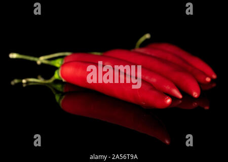 Gruppe von fünf ganze Hot red chili Cayenne auf schwarzem Glas isoliert Stockfoto