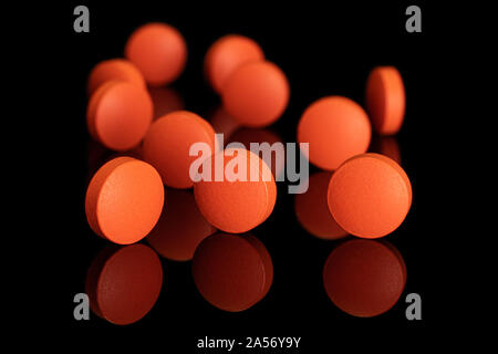 Eine Gruppe von elf ganze Orange tablet Apotheke auf schwarzem Glas isoliert Stockfoto