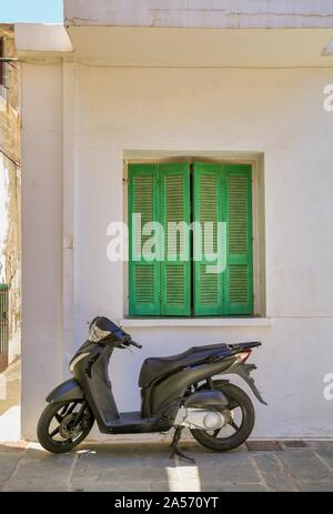 Einen schwarzen Roller und grünen Fensterläden Stockfoto