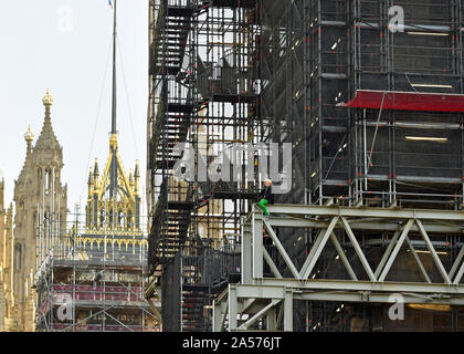 Ein Aussterben Rebellion Demonstrantin, die das Gerüst skaliert hat rund um Big Ben ist, ohne Seile an den Houses of Parliament, Westminster, London angebracht werden. Stockfoto