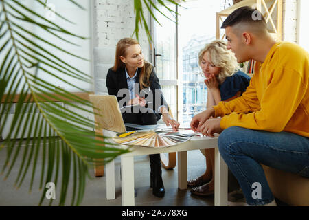 Interior Designer arbeiten mit jungen Paar. Sehr nette Familie und professionellen Designer oder conept architector Erörterung künftiger Innenraum, Arbeiten mit Farbpalette, Zimmer Zeichnungen in modernen Büro. Stockfoto