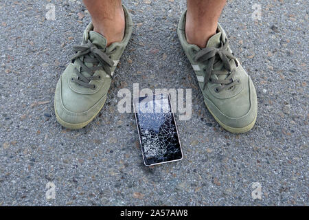 Smartphone fiel auf eine Straße. Gebrochene Handy. Handy fiel aus meiner Tasche. Kerl gefunden Handy ist beschädigt. Stockfoto