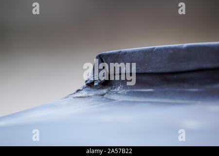 Schließen Sie die Tropfen Wasser die Rinne fließt. Blaue Rinne und schmelzender Schnee, der in Form eines Tropfens fließt Stockfoto