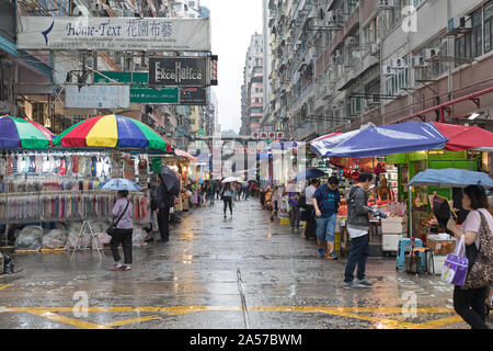 Kowloon, Hong Kong - 23. April 2017: Käufer unter den Sonnenschirmen auf der Straße Markt regnerischen Tag in Kowloon, Hong Kong. Stockfoto