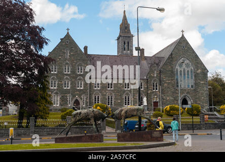 In Killarney, Irland - 14. Juni, 2019: der Kampf gegen Rote Hirsch Statue und Kirche Architektur in Killarney, County Kerry Irland. Killarney ist eine Population Stockfoto