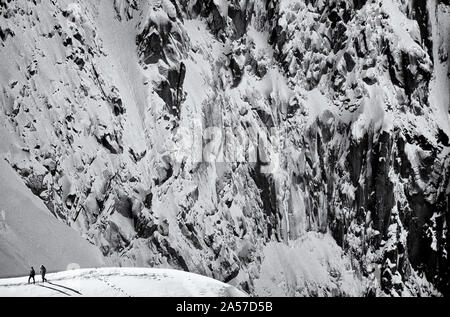 Zwei Bergsteiger auf dem Schneegrat mit der schieren West Angesichts der Aiguille de planen darüber hinaus in der Aiguilles von Chamonix, Frankreich Stockfoto