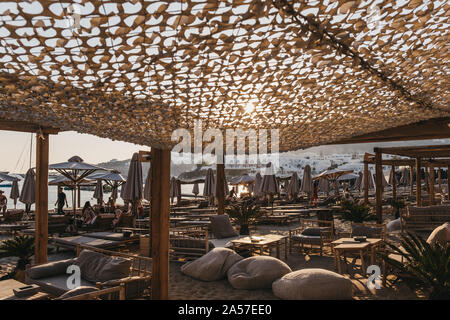 Mykonos, Griechenland - 19. September 2019: Tabellen und Reihen von Liegestühlen und Sonnenschirmen auf Platis Gialos, einem beliebten Strand an der Südküste von Mykonos. Wählen Sie Stockfoto