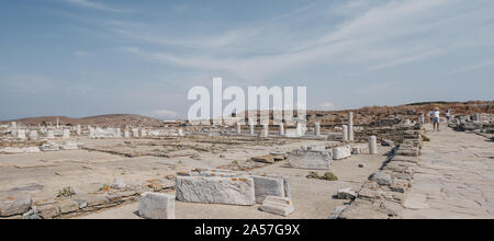 Delos, Griechenland - 20. September. 2019: Ruinen von Agora auf der historischen Insel Delos, Griechenland, das Archäologische Museum von Delos im Hintergrund. Menschen w Stockfoto