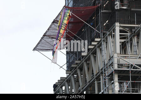 Westminster, London, UK, 18. Okt 2019. Ein Klima Demonstrant vor dem Aussterben Rebellion (XR) hat kletterte Big Ben auf halbem Weg, zwei Banner montiert und sitzt auf einige Gerüste auf der southeatern Ecke der Elizabeth Tower, allgemein bekannt als Big Ben, das Parlamentsgebäude. Polizei Verhandlungsführer Erscheinen auf der Szene gerade über Ihn zu werden. Credit: Imageplotter/Alamy leben Nachrichten Stockfoto