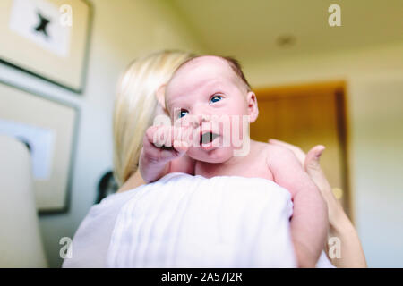 Blick über die Schulter eines neugeborenen Jungen in den Armen seiner Mutter Stockfoto