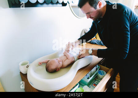 Einen neuen Papa seinen neugeborenen Windel auf einem Wickeltisch Stockfoto
