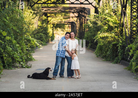 Bezaubernd lächelnde Blonde 4-jährige Mädchen in sundress in der Nähe von üppiger Pflanzen Stockfoto