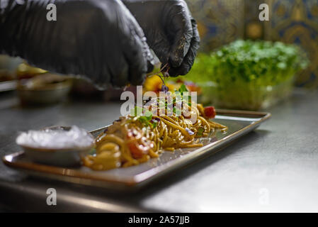 Essen Konzept. Der Koch ist mit frischen Kräutern und Blumen Gerichte im Restaurant eingerichtet. Der Prozess der Herstellung Spaghetti mit Meeresfrüchten. Stockfoto