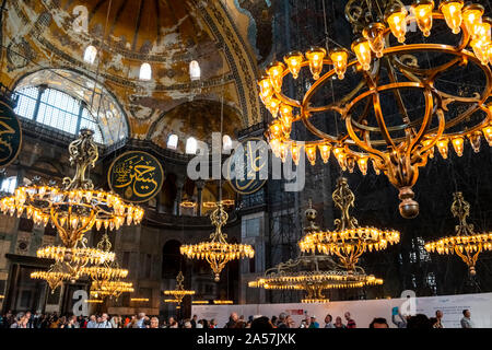 Blick auf die Decke und den oberen Ebene als Touristen sammeln unter den Kronleuchtern der Hagia Sophia Museum, eine ehemalige Moschee in Istanbul, Türkei. Stockfoto