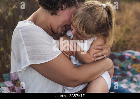 Mama kuscheln 4 Jahre altes Mädchen im Freien auf quilt Stockfoto