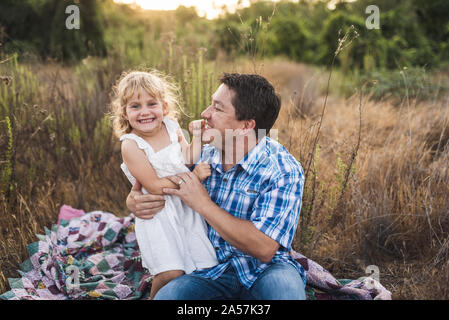 Lachend Vater und Tochter auf Patchwork Quilt in einer Wiese Stockfoto