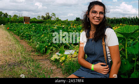 Muslimische Mädchen sitzt auf dem Boden lächelnd vor Pumpkin Patch im Herbst in Florida Stockfoto
