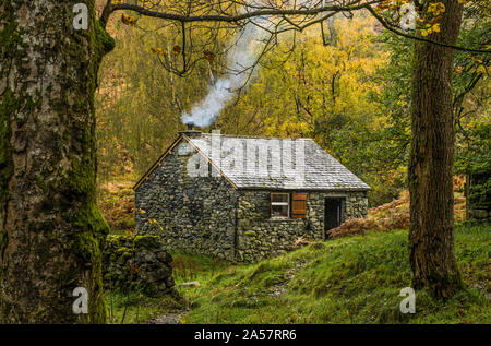 Hütte aus Stein mit Rauch aus dem Schornstein in der Nähe von Ashness Brücke im Lake District National Park im Herbst Stockfoto