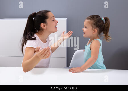 Eine attraktive junge Frau hilft das Mädchen wie Auszusprechen, die Geräusche im Büro Stockfoto