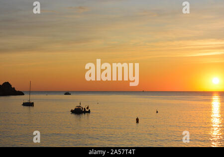 Yacht und Boot von der Landspitze verankert, Cabo La Nao, Silhouette bei Sonnenaufgang Stockfoto