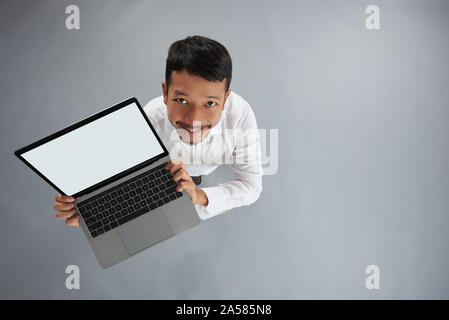 Junger Mann halten Laptop oben Draufsicht auf Grau studio Hintergrund Stockfoto