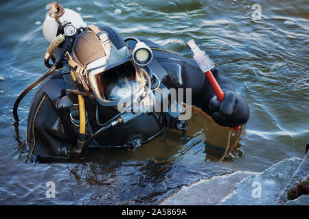 Industrielle Taucher mit Ausrüstung und einem Hammer in das Wasser am Ufer Verstärkung arbeiten, kopieren Raum Stockfoto