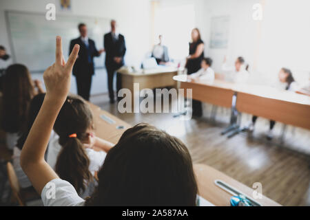 Flache Tiefenschärfe Bild mit einem Schüler erhobenen Hand zu beantworten eine Frage oder für eine Aufgabe in der Schule zu engagieren. Stockfoto