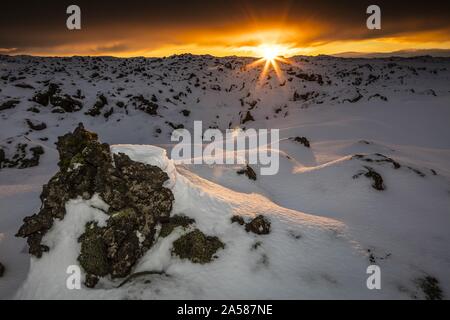 Atemberaubender Sonnenuntergang über einem verschneiten Feld in Lava Field, Island Stockfoto