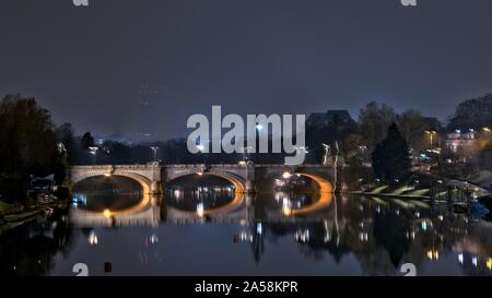 Horizontale Aufnahme der Betonbrücke wunderschön im See unter dem Nachthimmel in Turin, Italien reflektiert Stockfoto