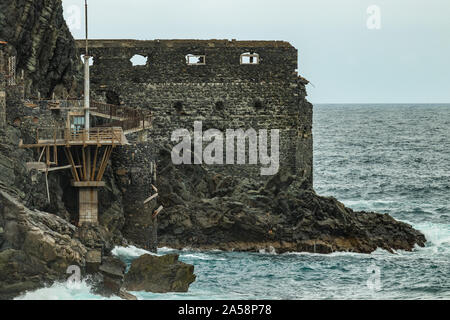 Vallehermoso Strand in La Gomera mit riesigen Wellen, auf Basaltgestein. Alte Gebäude aus Stein namens El Castillo del Mar, einem alten banana Factory. Schuß durch Stockfoto