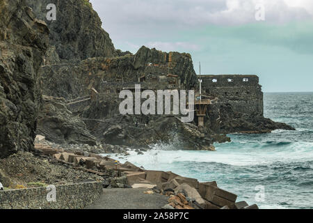 Vallehermoso Strand in La Gomera mit riesigen Wellen, auf Basaltgestein. Alte Gebäude aus Stein namens El Castillo del Mar, einem alten banana Factory. Schuß durch Stockfoto