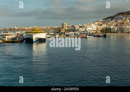Hafen in Los Cristianos, Teneriffa, Spanien - Mai 25, 2019: Auf der linken Seite - Fähre Fred Olsen auf La Gomera am frühen Morgen in den Hafen von Los Cristianos dock Stockfoto